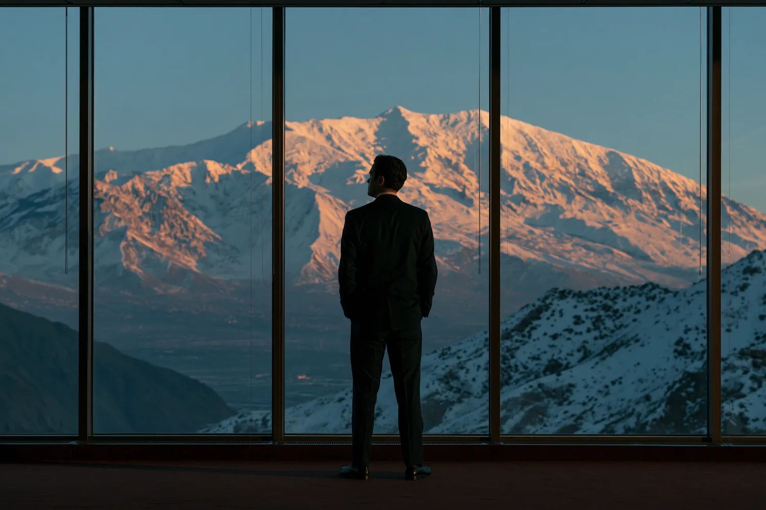 Hombre de espaldas frente a la cordillera desde una oficina